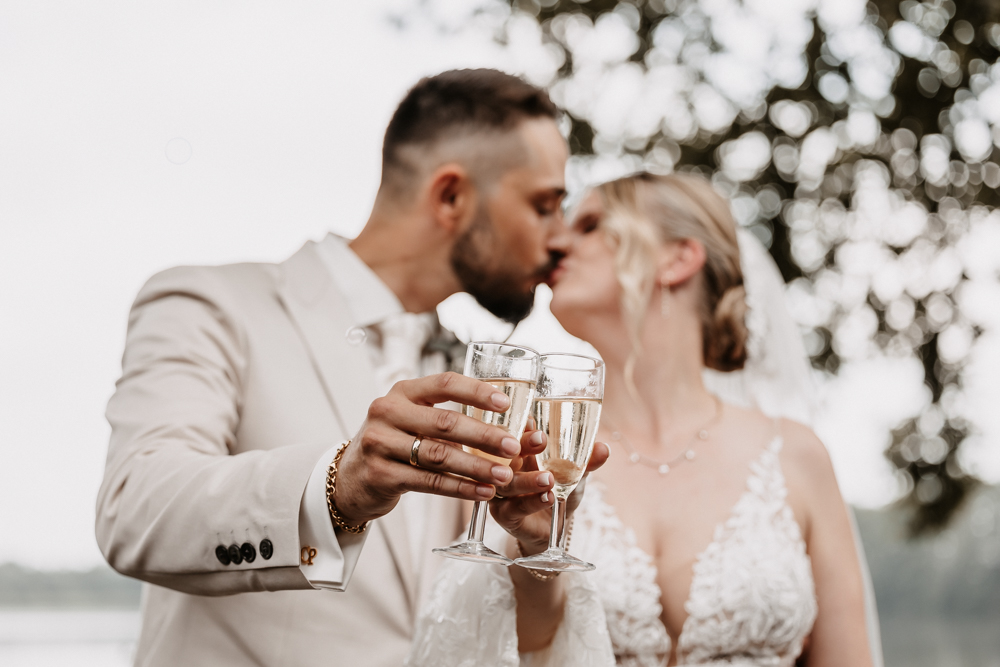 Brautpaar stößt mit Sektgläsern an und küsst sich, Hochzeitsfotografin Hamburg